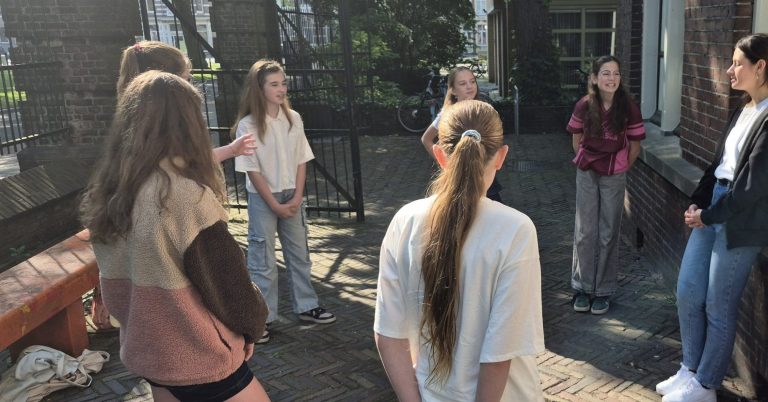 Een man met een pet, met open mond en handen op zijn wangen, toont verrassing.